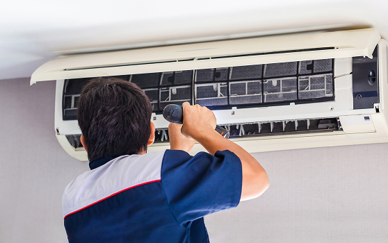 repairman using screwdriver fixing modern air conditioner